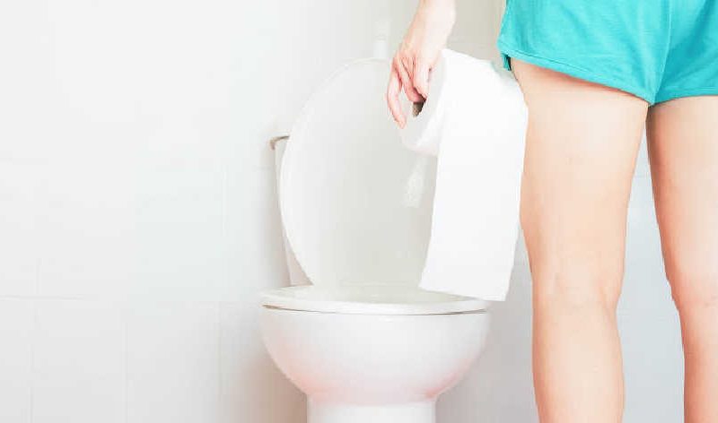 woman in front of the toilet with toilet paper