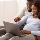 pregnant couple on a laptop