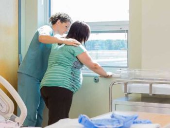 pregnant woman up walking in the hospital with her nurse.