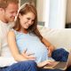 pregnant couple looking at a laptop