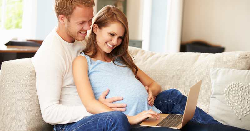 pregnant couple looking at a laptop