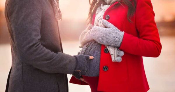 pregnant couple in coats