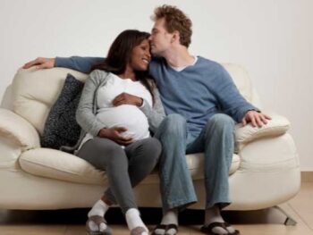 pregnant couple cuddling on the couch.