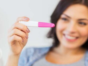 woman looking at a pregnancy test with a positive sign.