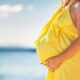 pregnant woman in a yellow dress on the beach