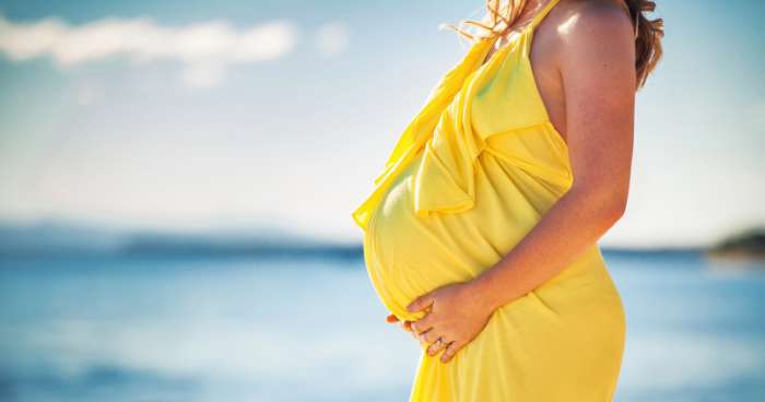 pregnant woman in a yellow dress on the beach