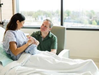 husband and wife in a hospital room with their newborn