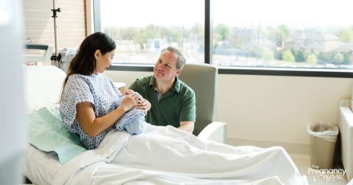 husband and wife in a hospital room with their newborn