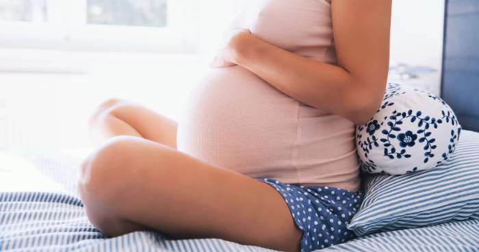 pregnant woman sitting on bed